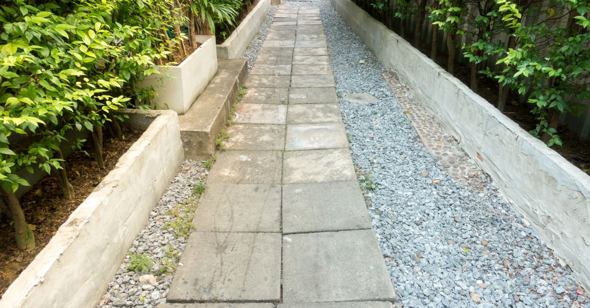 Jardín doméstico con senderos de ladrillo, plantas de sombra y banco de hierro